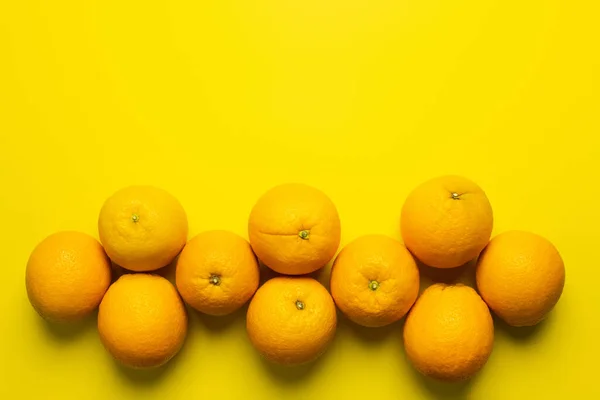 Colocación plana con naranjas orgánicas con sombra sobre fondo amarillo - foto de stock