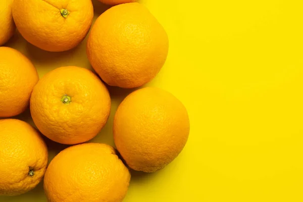 Vista superior de naranjas enteras sobre fondo amarillo - foto de stock