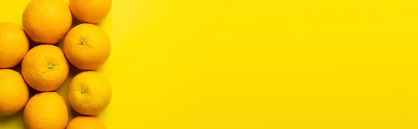 Vista dall'alto di arance naturali in buccia su sfondo giallo, banner — Foto stock