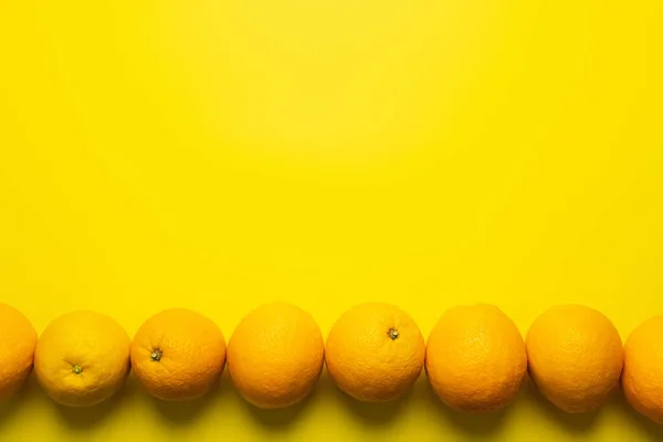 Flat lay com laranjas em linha sobre fundo amarelo — Fotografia de Stock