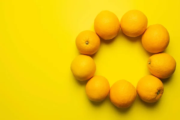 Vista dall'alto di arance a forma di cornice su sfondo giallo — Foto stock