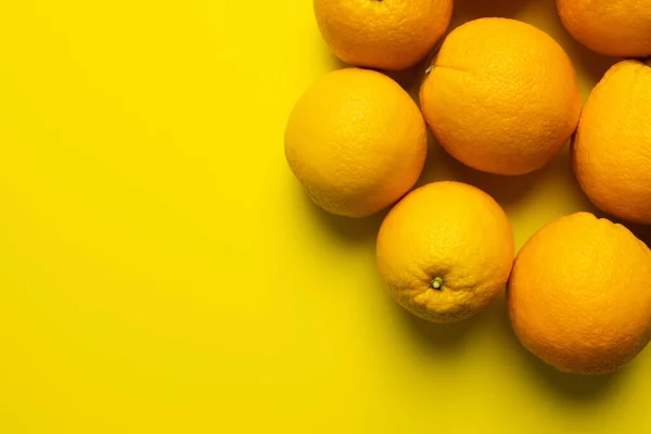 Top view of ripe oranges in peel on yellow background - foto de stock