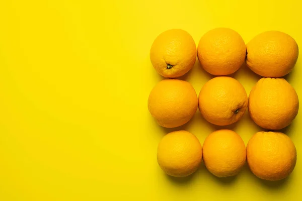 Pose plate d'oranges en forme carrée sur fond jaune — Photo de stock