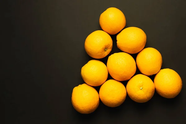 Flat lay with oranges in triangle form isolated on black — Stock Photo