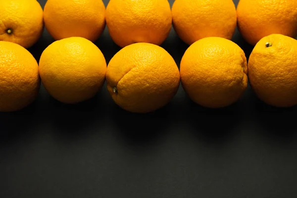 Colocación plana con naranjas naturales en líneas sobre fondo negro - foto de stock