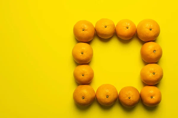 Colocação plana com quadro de tangerinas no fundo amarelo — Stock Photo