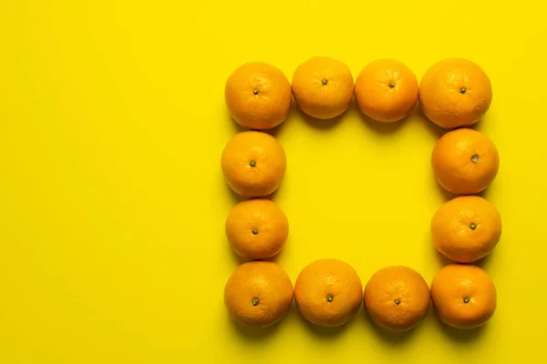 Colocación plana con marco de mandarinas sobre fondo amarillo - foto de stock