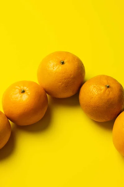 Vista de alto ângulo de tangerinas na casca no fundo amarelo — Fotografia de Stock