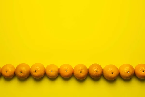 Flat lay with tangerines in line on yellow background with copy space — Stock Photo
