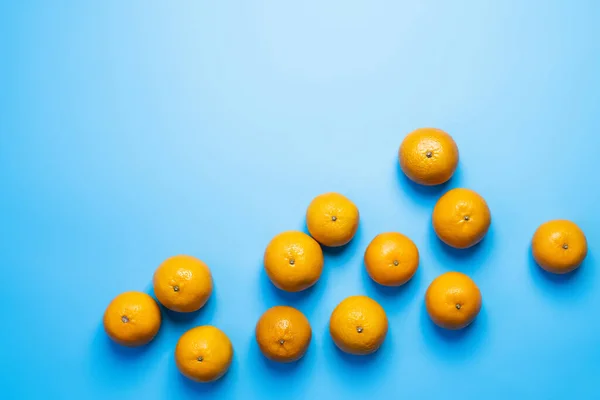 Vista superior de mandarinas brillantes sobre fondo azul - foto de stock