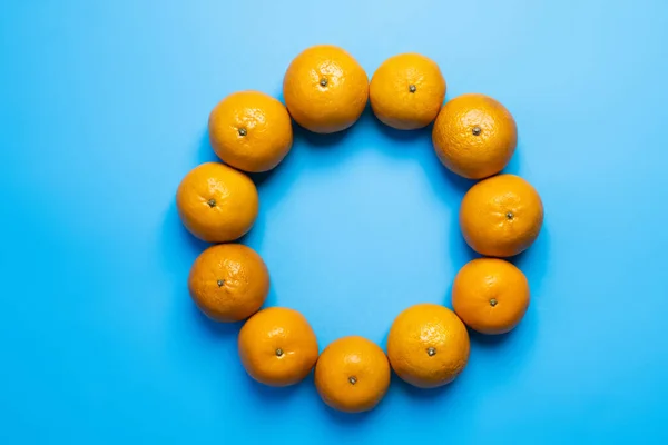 Pose plate avec des mandarines en forme ronde sur fond bleu — Photo de stock