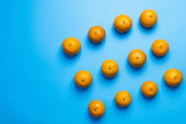 Colocación plana de mandarinas naturales sobre fondo azul - foto de stock