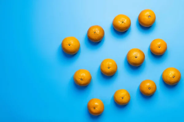 Flat lay of natural tangerines on blue background - foto de stock