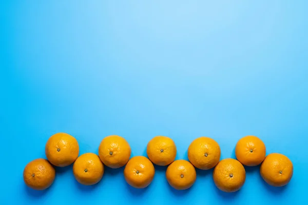 Piso con mandarinas brillantes con sombra sobre fondo azul - foto de stock