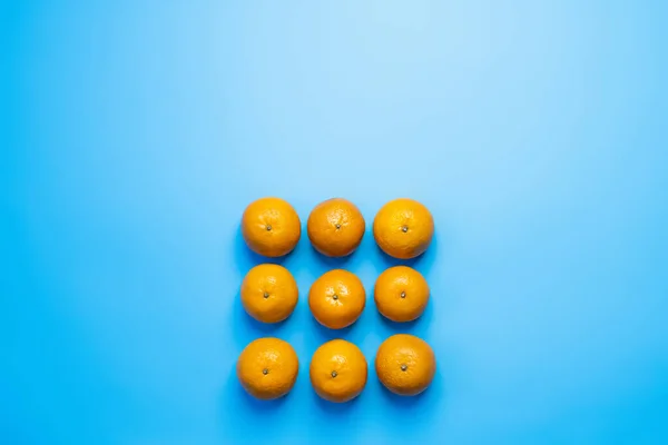 Colocación plana con mandarinas en forma cuadrada sobre fondo azul - foto de stock
