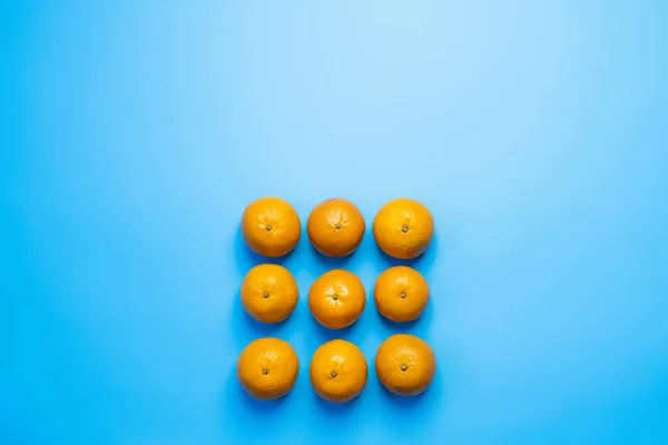 Flat lay with tangerines in square shape on blue background — Stockfoto