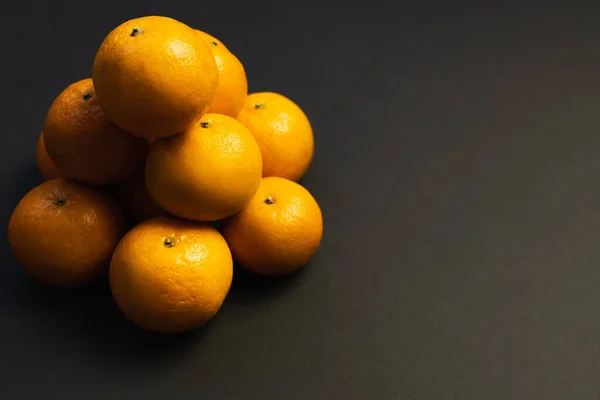 Tangerinas empilhadas em fundo preto com espaço de cópia — Fotografia de Stock