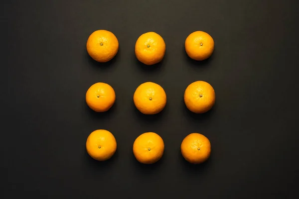 Colocación plana con mandarinas brillantes sobre fondo negro - foto de stock