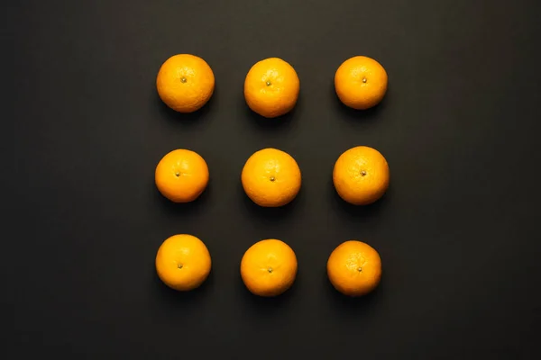 Flat lay with bright tangerines on black background — Foto stock