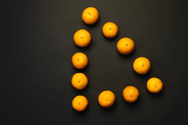 Flat lay with natural tangerines in triangle form on black background - foto de stock