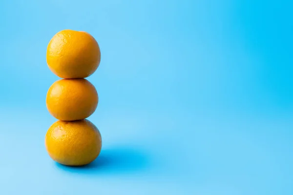 Mandarines empilées sur une surface bleue avec ombre — Photo de stock