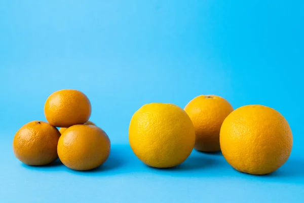 Natürliche Mandarinen und Orangen auf blauem Hintergrund — Stockfoto