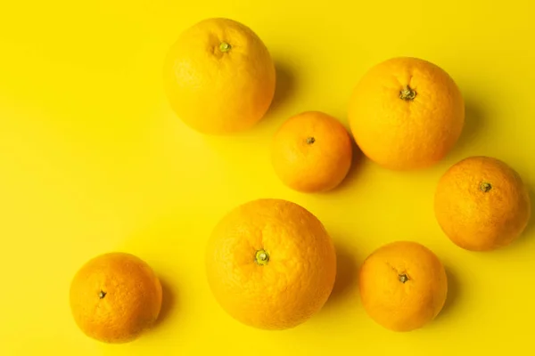 Top view of fresh oranges and mandarins on yellow background — Fotografia de Stock