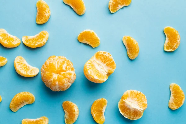 Vue du dessus des mandarines pelées sur fond bleu — Photo de stock