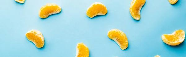 Top view of lobules of sweet mandarins on blue background, banner - foto de stock