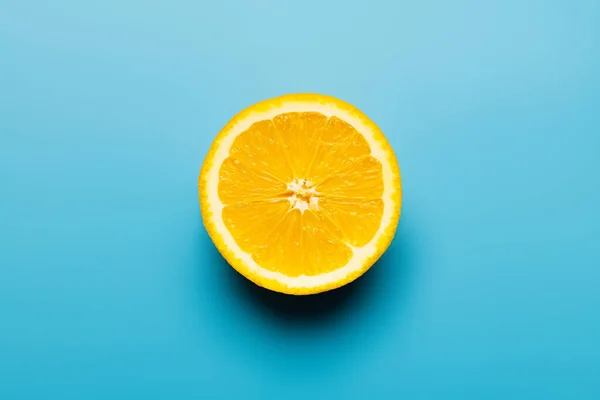 Draufsicht auf geschnittenes Orange mit Schatten auf blauem Hintergrund — Stockfoto