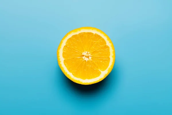 Top view of cut orange with shadow on blue background — Stock Photo