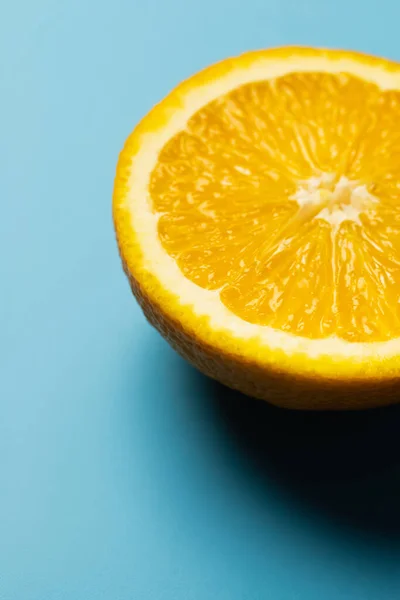 Закрыть вид на сочный и разрезанный апельсин на синем фоне — стоковое фото