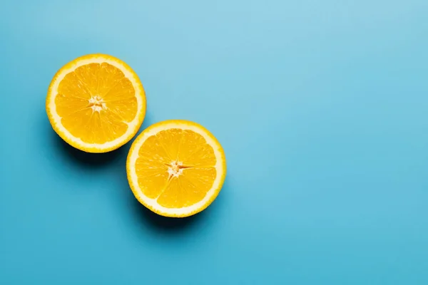 Top view of cut oranges with shadow on blue background with copy space — Stock Photo