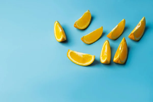 High angle view of fresh pieces of oranges with shadow on blue background - foto de stock