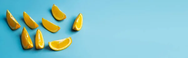 Vista de ángulo alto de naranjas cortadas sobre fondo azul, bandera - foto de stock