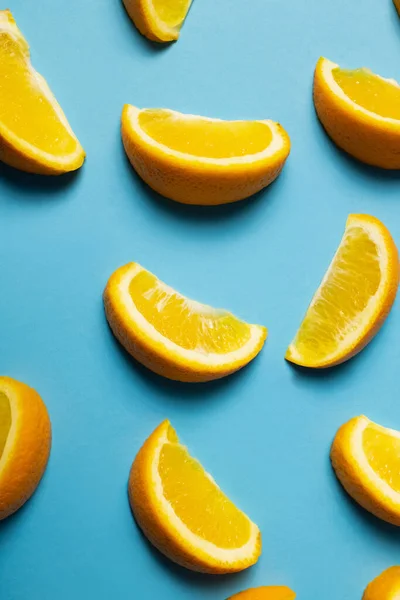 Vue de dessus des morceaux d'oranges avec ombre sur fond bleu — Photo de stock