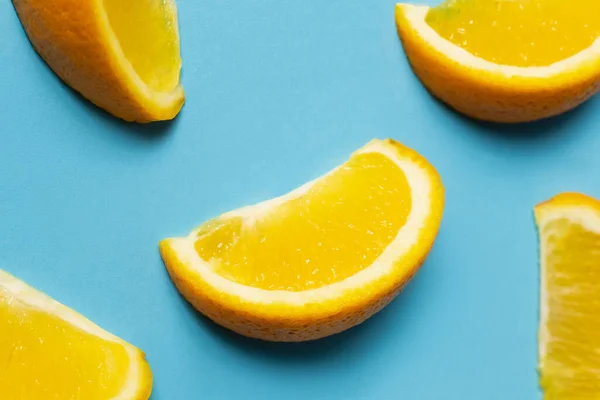 Vista de cerca de jugosas piezas de naranja sobre fondo azul - foto de stock