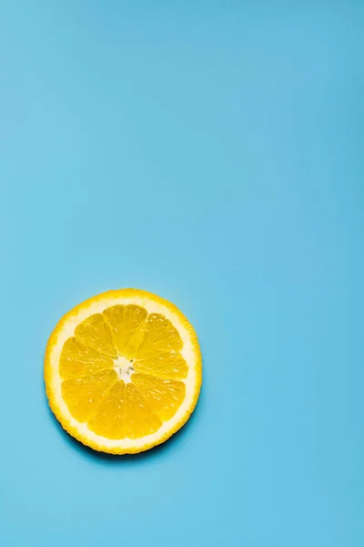 Top view of slice of sweet orange on blue surface with copy space — Stock Photo
