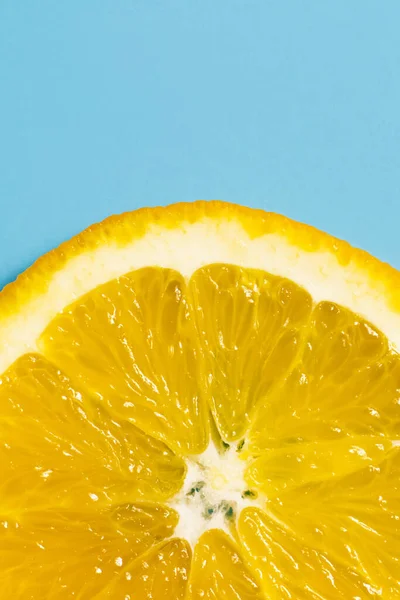 Close up view of juicy slice of orange on blue surface — Photo de stock