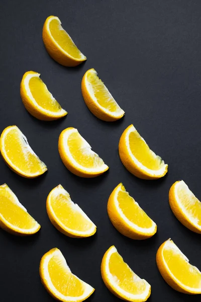 Flat lay com pedaços de laranjas em fundo preto — Fotografia de Stock