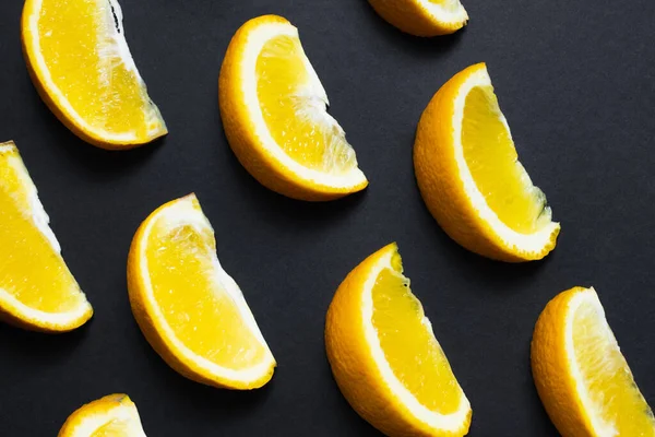 Flat lay with pieces of sweet oranges on black background — Stockfoto