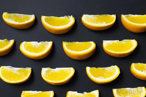 Colocação plana de pedaços de laranjas naturais no fundo preto — Stock Photo