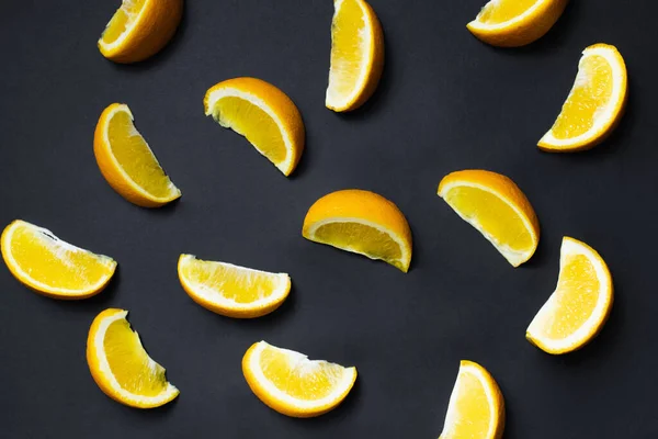 Верхний вид кусочков спелых апельсинов на черном фоне — стоковое фото