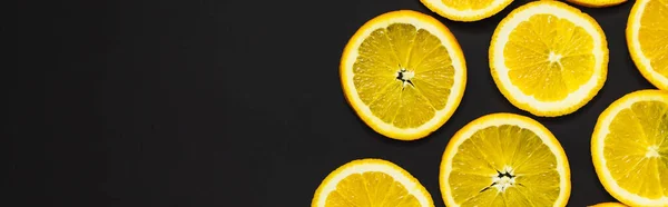 Top view of cut and bright orange slices isolated on black, banner — Fotografia de Stock