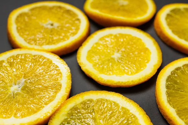 Close up view of bright slices of fresh oranges on black background — Fotografia de Stock