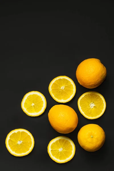 Draufsicht auf natürliche ganze und geschnittene Orangen isoliert auf schwarz — Stockfoto