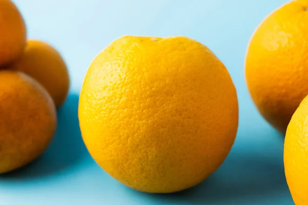 Close up view of oranges near blurred tangerines on blue surface — Fotografia de Stock