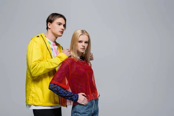 Young stylish couple in colorful clothes posing isolated on grey — Photo de stock