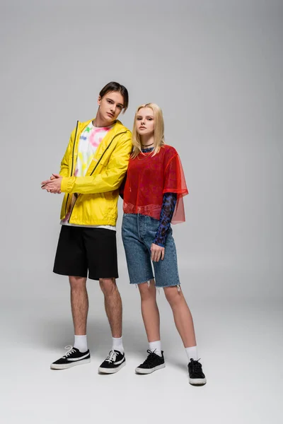 Young man in windbreaker standing near blonde girlfriend on grey background — Stockfoto