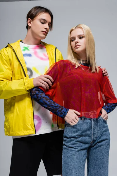 Stylish man hugging blonde girlfriend while posing on grey background — Photo de stock